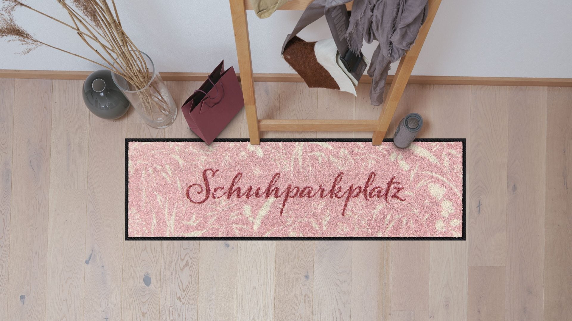 Salonloewe Schuhparkplatz mit Schriftzug und cremefarbenen Gräsern auf rosa Hintergrund ambiente