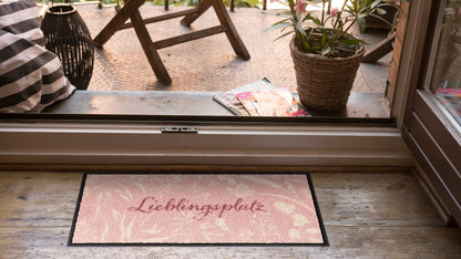 Salonloewe Fußmatte mit Lieblingsplatz-Schriftzug und cremefarbenen Gräsern auf Rosa ambiente